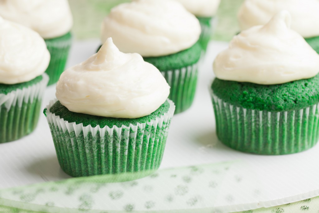 Side view of St. Patrick's Day green velvet cupcakes piped with a decadent cream cheese frosting on glitter tule fabric